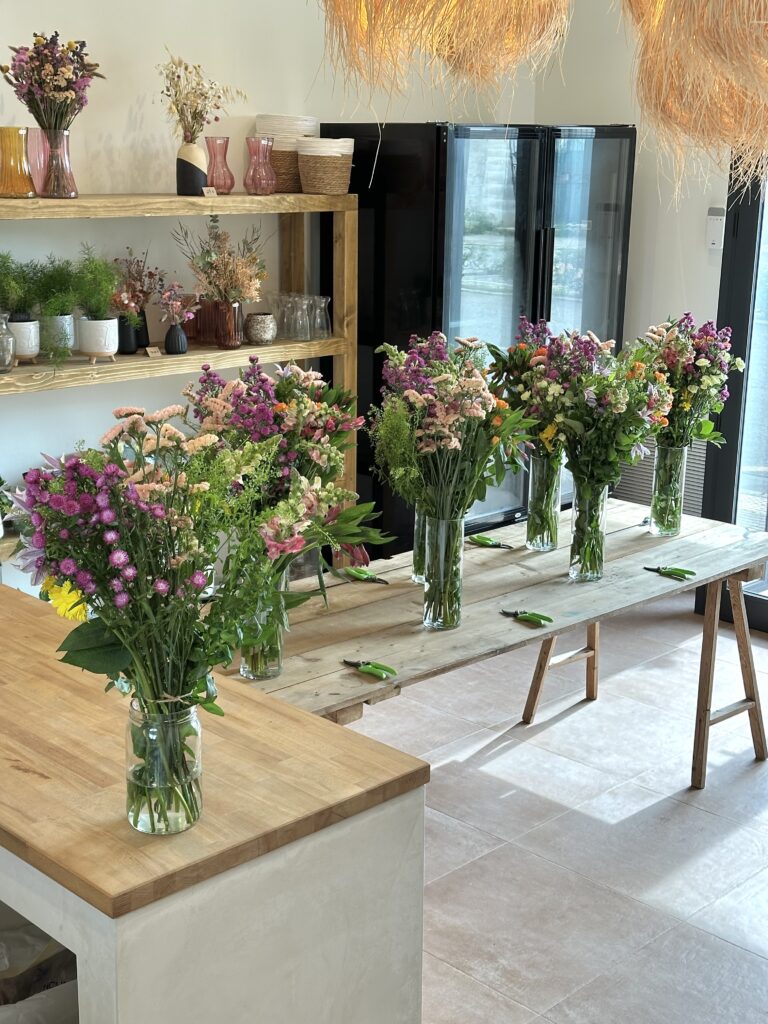 Espacio de taller floral con ramos en proceso de diseño, colocados en jarrones sobre una mesa de madera.