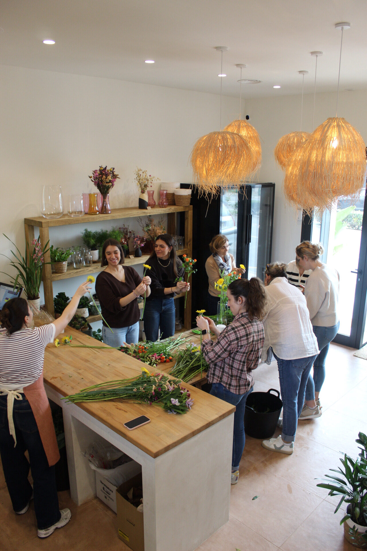 Grupo de personas en un taller de arreglos florales, trabajando juntas en la creación de ramos.
