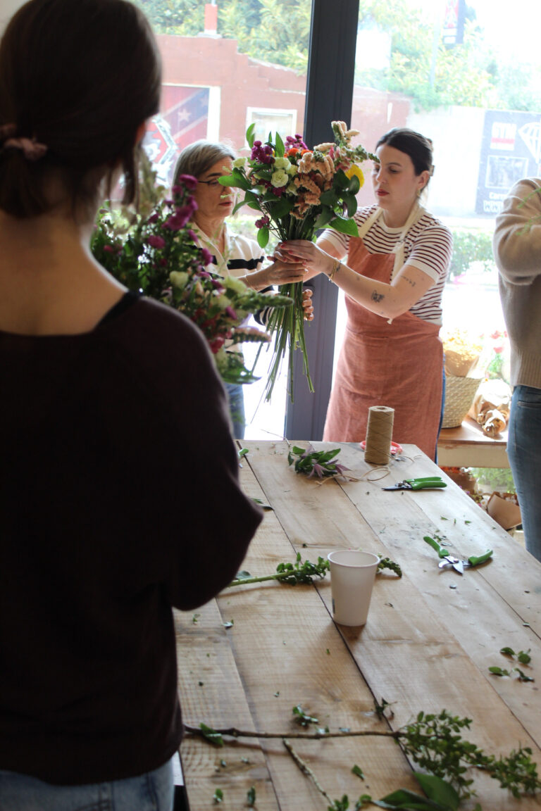 Personas participando en un taller floral, aprendiendo a crear ramos con diferentes tipos de flores.