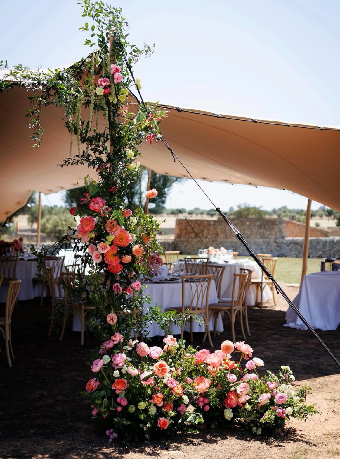 Gran centro floral de flores naturales coloridas con decoración elevada en carpa de boda
